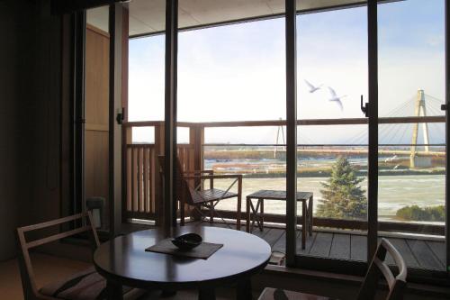 a table and chairs in a room with a large window at Tokachigawa Onsen Daiichi Hotel in Otofuke