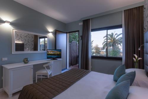 Hotel Airone isola d'Elba في بورتوفيرّايو: غرفة نوم مع سرير ومكتب مع جهاز كمبيوتر
