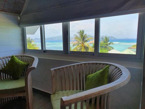a room with two chairs and a view of the ocean at Bord Mer City Apartments in La Digue