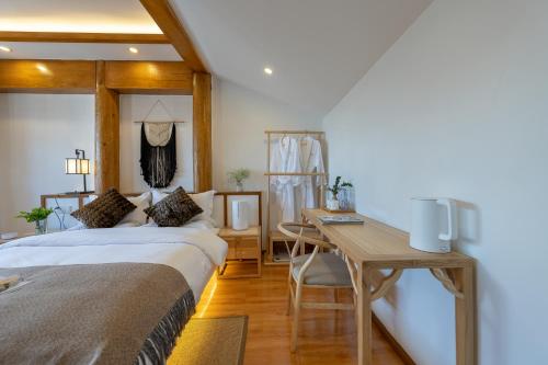 a hotel room with a bed and a desk at 丽江慕云堂观景客栈Lijiang Muyuntang View Hotel in Lijiang