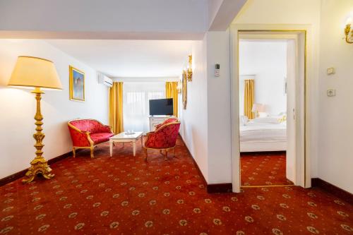 アルバ・ユリアにあるHotel Cetateのベッド、テーブル、椅子が備わるホテルルームです。