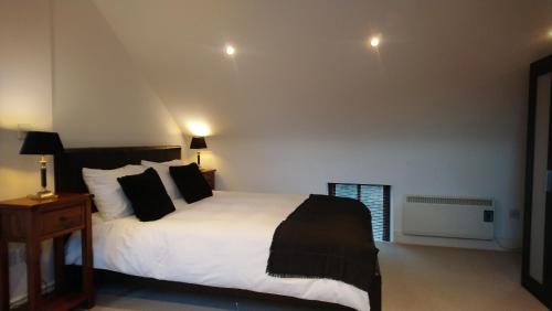 a bedroom with a bed with white sheets and black pillows at 10 The Kiln in Westport