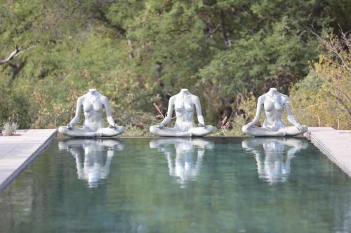 three statues sitting in the water in the water at Palala Boutique Game Lodge and Spa in Tom Burke