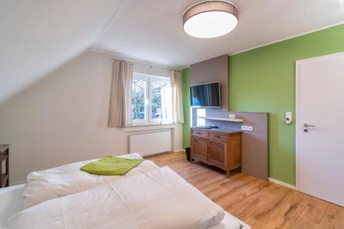 een slaapkamer met groene muren, een bed en een bureau bij Das Eifelfels in Kreuzau