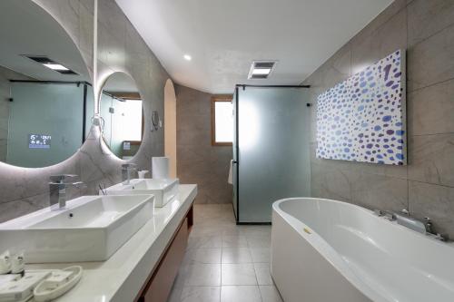 a bathroom with two sinks and a tub and mirrors at 丽江慕云堂观景客栈Lijiang Muyuntang View Hotel in Lijiang