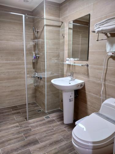 a bathroom with a toilet and a sink and a shower at Hermit Crab B&B in Wuqi
