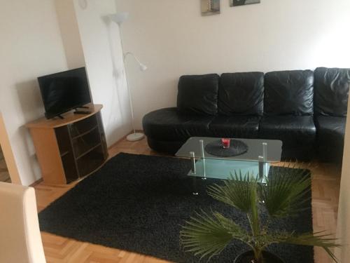 a living room with a black couch and a glass table at Apartman PEŠAČKA ZONA in Šabac