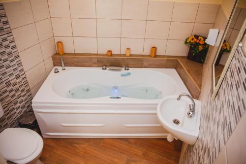 a bath tub in a bathroom with a toilet and a sink at King Arthur Panzió in Baja