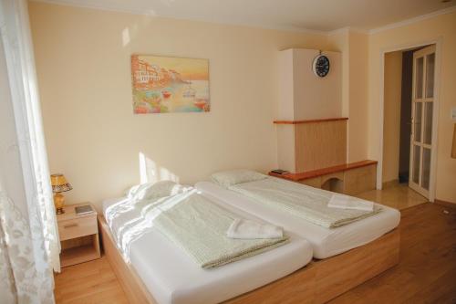 a bedroom with two beds and a painting on the wall at King Arthur Panzió in Baja