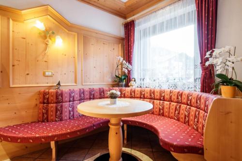 a red couch with a table and a window at Garni Edera in Corvara in Badia