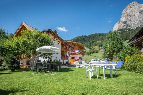 a house with a table and chairs in the grass at Garni Edera in Corvara in Badia