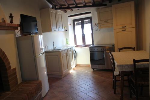 a kitchen with a refrigerator and a table and a window at La Casina di Nonna Lola in Castiglione dʼOrcia