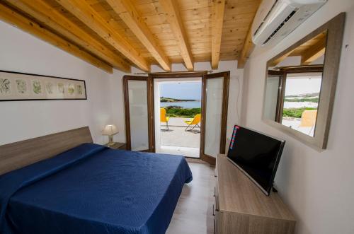a bedroom with a bed and a television and a balcony at A.I.R. Villa Marinedda in Isola Rossa