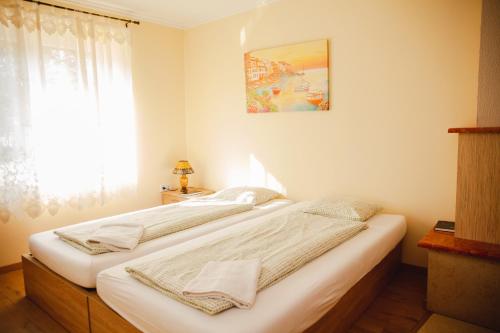 two beds in a bedroom with a window at King Arthur Panzió in Baja