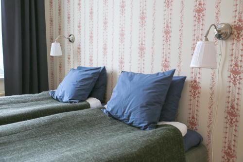 two beds with blue pillows in a bedroom at Polhem Bed & Breakfast in Falun