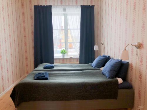 a bedroom with a bed with blue pillows and a window at Polhem Bed & Breakfast in Falun