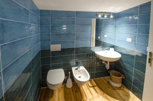 bagno piastrellato blu con servizi igienici e lavandino di A.I.R. Villa Marinedda a Isola Rossa