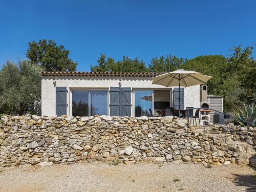 a stone wall in front of a house with an umbrella at Modern holiday home with private pool in Brignoles