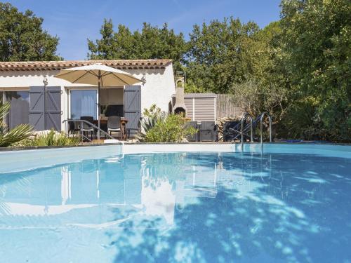 a swimming pool with an umbrella and a house at Modern holiday home with private pool in Brignoles