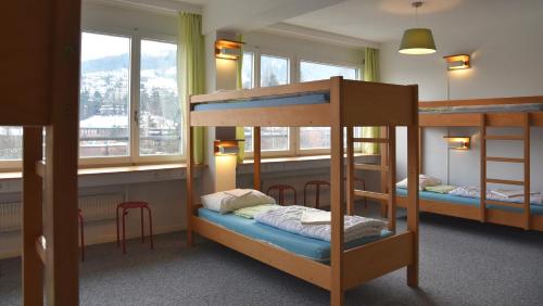 a bunk bed room with two bunk beds and windows at Hostel 77 Bern in Bern