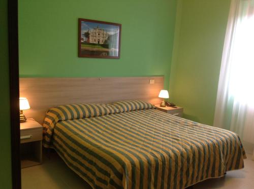 a hotel room with a bed and two tables and two lamps at Hotel Certosa in Certosa di Pavia