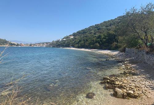 a beach with rocks and water and a mountain at Imerolia Studios in Kassiopi