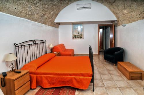 a bedroom with an orange bed and a chair at Il Giardino Del Barocco in Noto