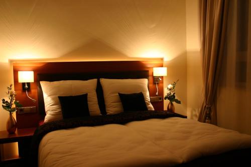 a bedroom with a large bed with two lamps at Hotel Kleine Festung Germersheim in Germersheim