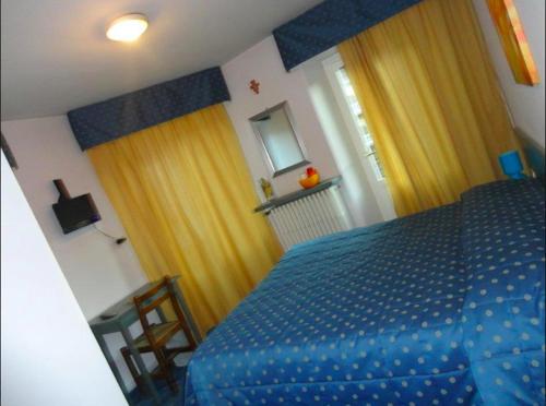 - une chambre avec un lit bleu et des rideaux jaunes dans l'établissement Albergo Centrale, à Fino del Monte