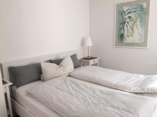 ein weißes Schlafzimmer mit einem Bett und einer Lampe in der Unterkunft Ferienwohnung Madeleine in Donzdorf