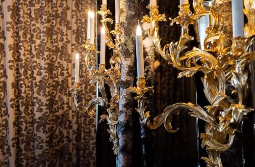 a gold chandelier with candles in front of a curtain at Grand Hôtel du Lion d'Or in Romorantin