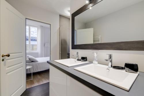 een badkamer met 2 wastafels en een spiegel bij Le Palais Gallien in Bordeaux