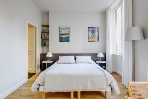 a white bedroom with a bed and two lamps at Le Palais Gallien in Bordeaux