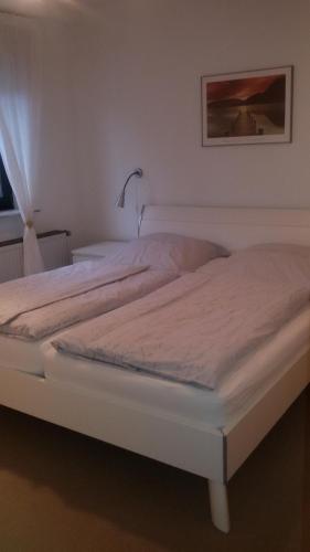 a white bed in a bedroom next to a window at Kelten-Ferienwohnung in Glauburg