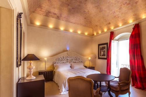 Palazzo Gattini Luxury Hotel في ماتيرا: غرفة نوم بسرير وطاولة وكراسي