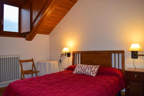 1 dormitorio con 1 cama con colcha roja en Duplex con vistas en Benasque, en Benasque
