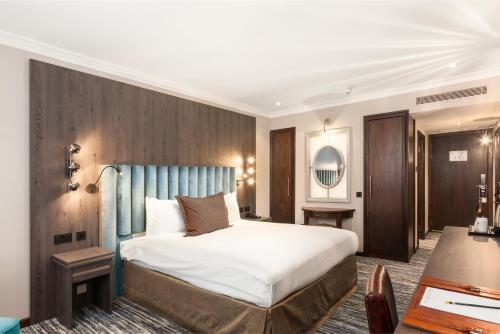 Schlafzimmer mit einem großen Bett mit blauem Kopfteil in der Unterkunft Courthouse Hotel London in London