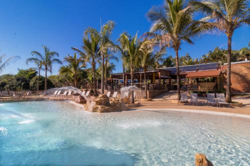 a pool at a resort with palm trees at Pousada Estalagem de Brotas in Brotas