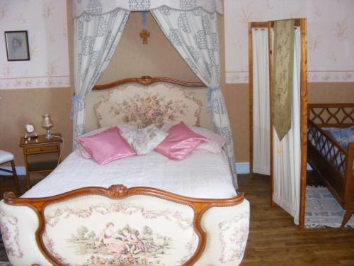 - une chambre avec un lit à baldaquin et des oreillers roses dans l'établissement La Mailholière, à Blanzay
