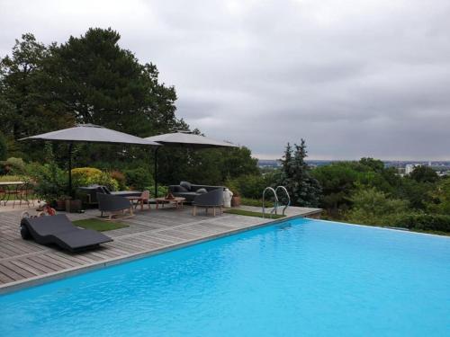una gran piscina con sillas y sombrillas junto a ella en LA MAISON DE ROBINSON en Le Plessis-Robinson