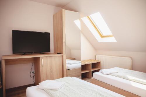 a room with two beds and a flat screen tv at King Arthur Panzió in Baja