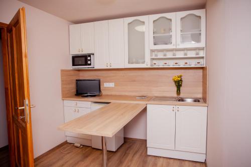 a kitchen with white cabinets and a wooden counter top at King Arthur Panzió in Baja