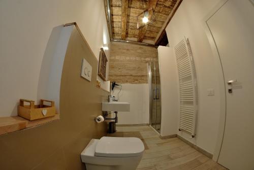 a bathroom with a white toilet and a wooden ceiling at B&B DEL CORSO in Loreto