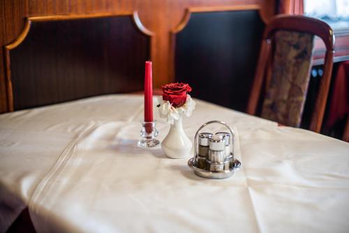 a table with a candle and a vase with a rose at Guesthouse Leski Dvor in Lesce