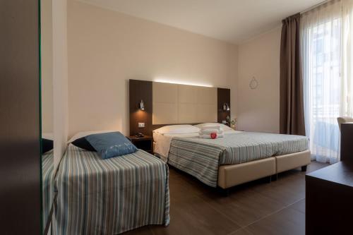 um quarto de hotel com duas camas e uma janela em Gimmi Hotel em Rimini