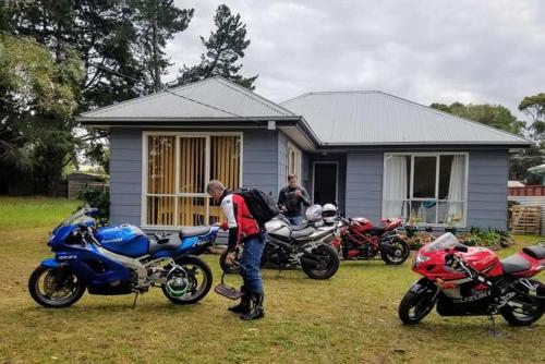 un homme debout devant une maison avec trois motocycles dans l'établissement Bellaghy Cottage, à Wimbledon Heights