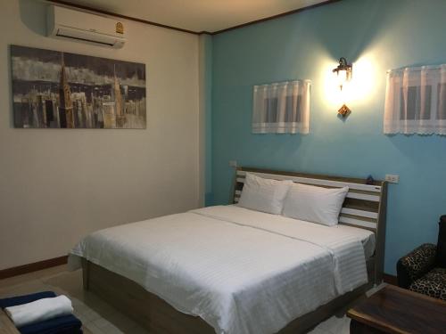 a bedroom with a white bed with a blue wall at Baan Penny in Phra Nakhon Si Ayutthaya