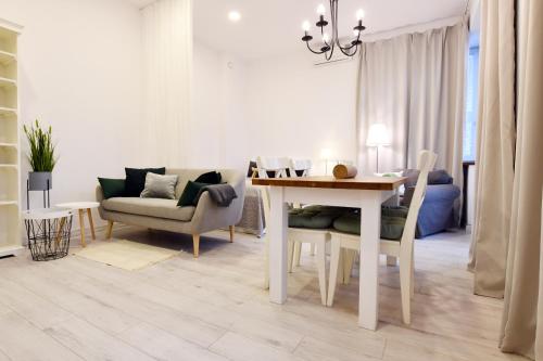 a white living room with a table and a couch at Vacaciones Towarowa Port II Kołobrzeg in Kołobrzeg