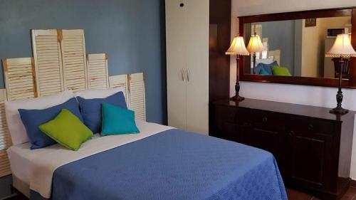 1 dormitorio con 1 cama con almohadas azules y verdes en Sandcastle Beach Apartments, en Palm-Eagle Beach