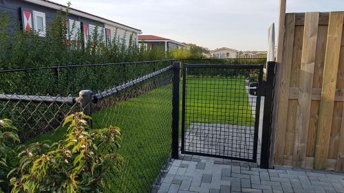 ein Zaun mit einem Tor in einem Garten in der Unterkunft Chalet Veere - eingezäunter Garten, hundefreundlich & ruhig in Zeeland in Serooskerke